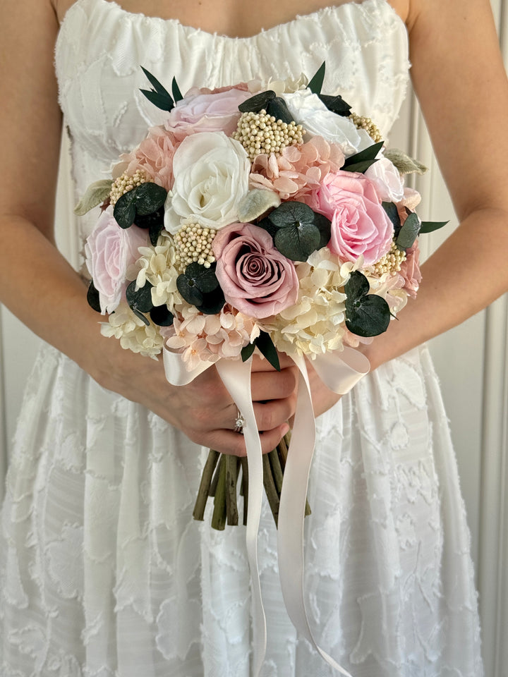 Bride holding Blush Affair bridal bouquet with blush and white roses, hydrangeas, and eucalyptus