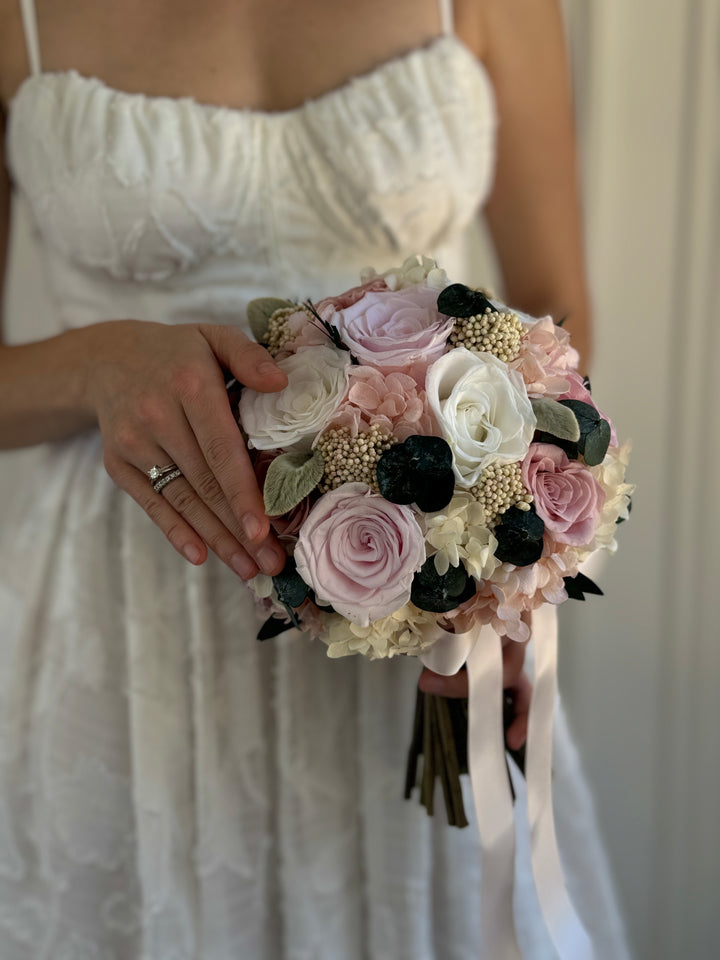 Romantic hand-tied bridal bouquet featuring soft pink roses, white hydrangeas, and greenery